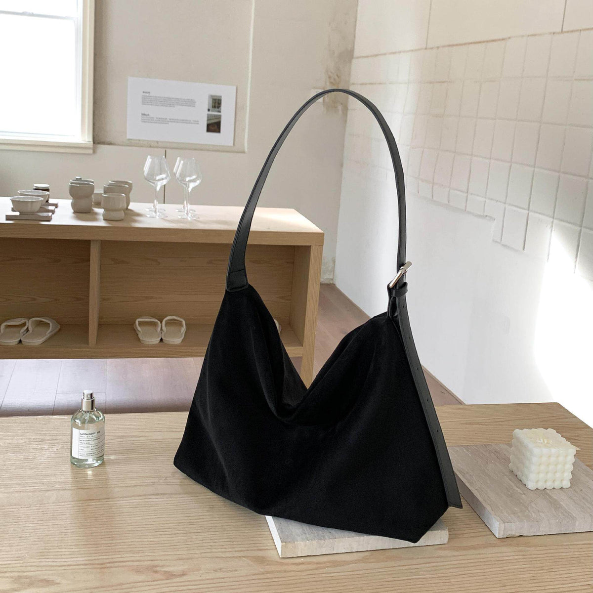 Sloane Suede Hobo Bag in black, on a table