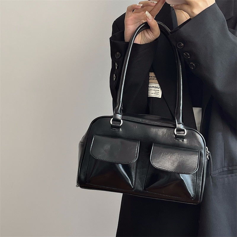 Romy Glossy Pocket Bag in black, held by hand