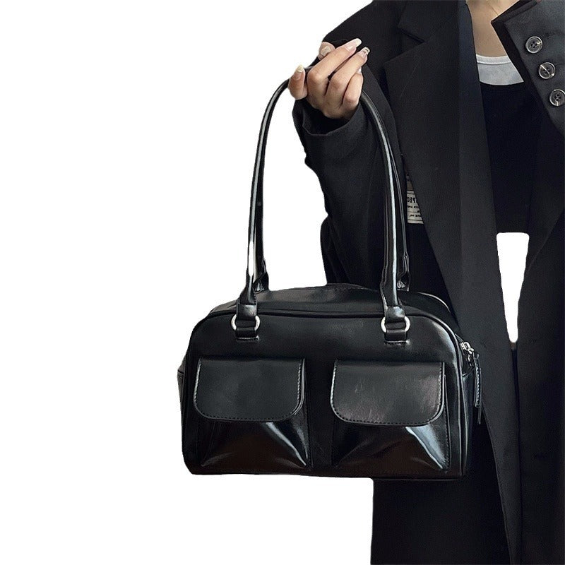 Romy Glossy Pocket Bag in black, held by hand, front