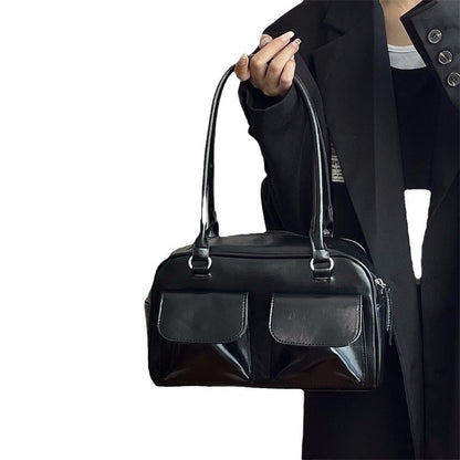Romy Glossy Pocket Bag in black, held by hand, front