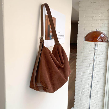 Sloane Suede Hobo Bag in brown, hanging on a wall
