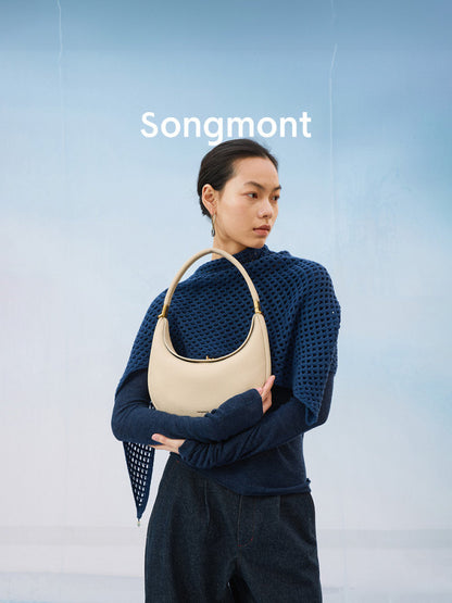 Aria Leather Crescent Bag in cream, held by a model