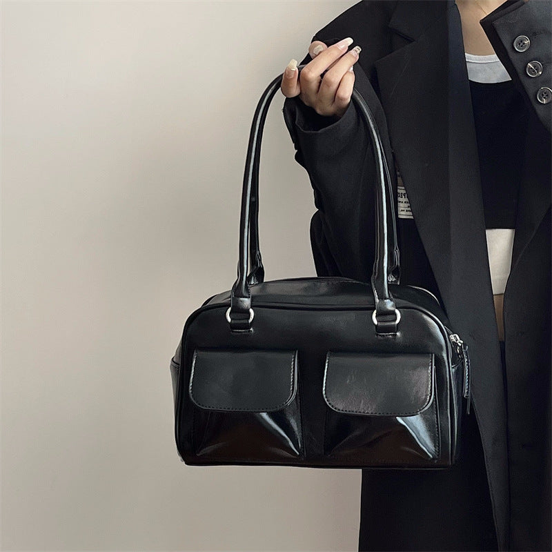 Romy Glossy Pocket Bag in black, held by hand
