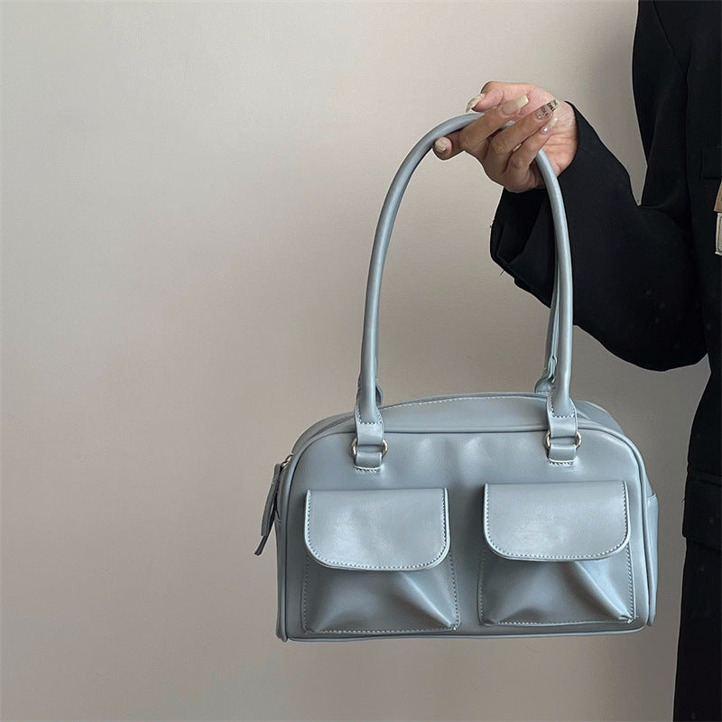 Romy Glossy Pocket Bag in blue, held by hand